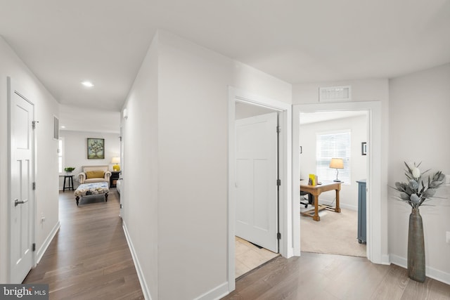 hall featuring light wood-style floors, recessed lighting, visible vents, and baseboards