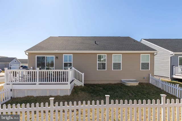 back of house with a shingled roof, fence, and a wooden deck