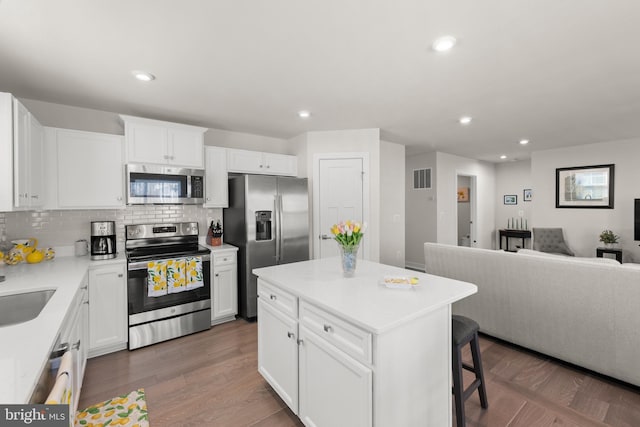 kitchen with stainless steel appliances, a center island, open floor plan, and white cabinetry