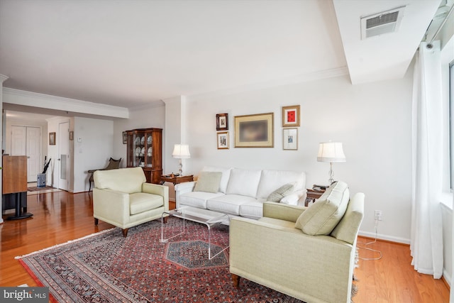 living room featuring baseboards, visible vents, wood finished floors, and ornamental molding