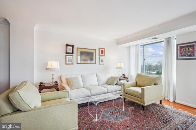 living area featuring visible vents, crown molding, baseboards, and wood finished floors