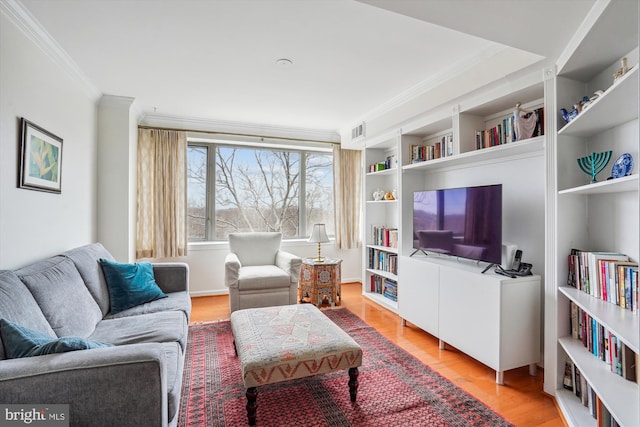 living area with light wood-style floors, visible vents, ornamental molding, and built in shelves