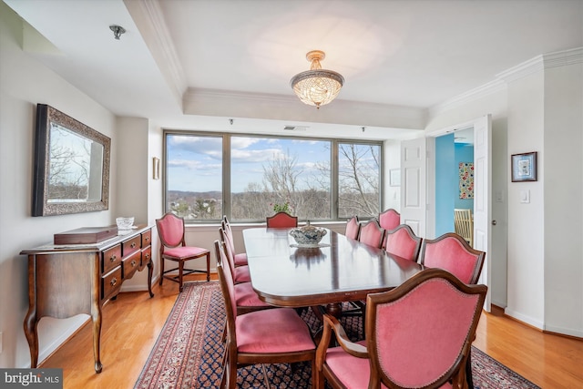 dining space featuring light wood-style flooring, visible vents, baseboards, and crown molding