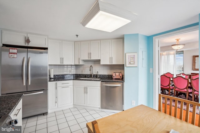 kitchen with light tile patterned floors, a sink, white cabinets, appliances with stainless steel finishes, and tasteful backsplash