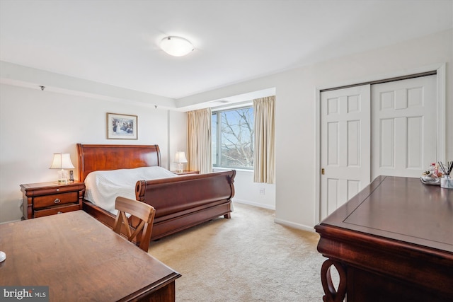 bedroom featuring a closet, light colored carpet, and baseboards