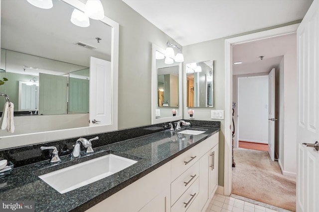 bathroom with double vanity, a sink, visible vents, and baseboards