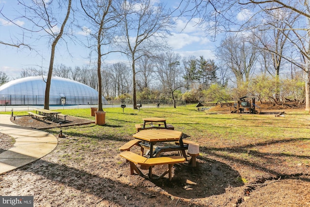 view of community featuring playground community, a lawn, and fence