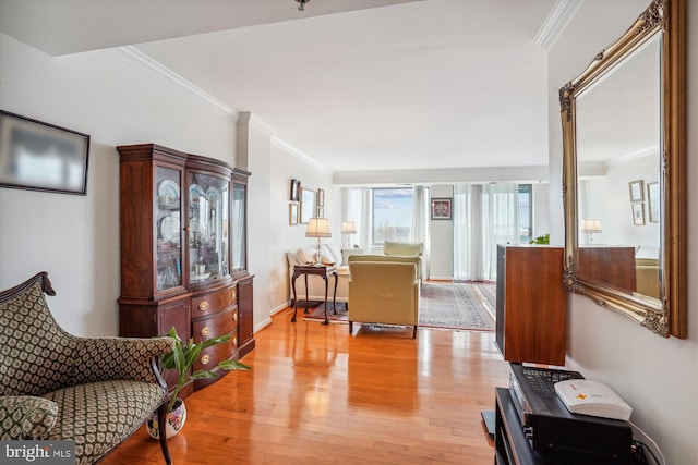 living room featuring light wood-style flooring, ornamental molding, and baseboards