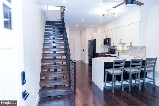 kitchen with stainless steel stove, light countertops, freestanding refrigerator, white cabinets, and a peninsula