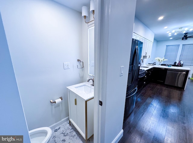 bathroom featuring recessed lighting, baseboards, wood finished floors, and vanity