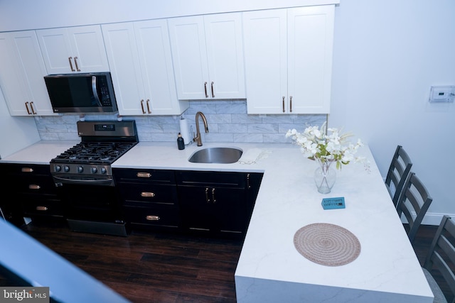 kitchen featuring dark cabinets, stainless steel appliances, a sink, white cabinetry, and decorative backsplash