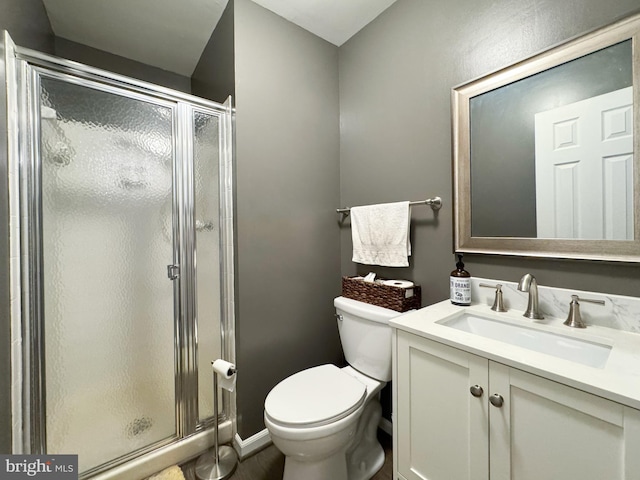 bathroom featuring toilet, a stall shower, and vanity