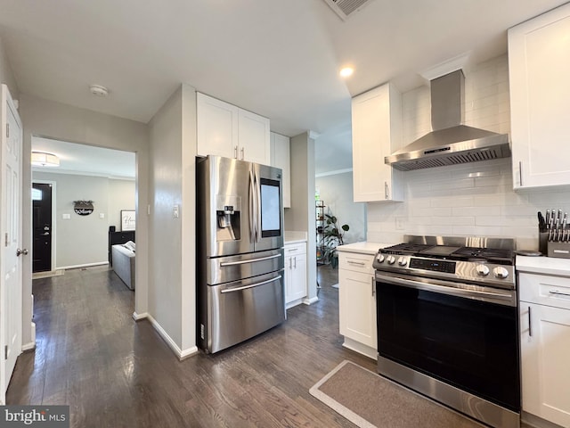 kitchen featuring dark wood-style flooring, stainless steel appliances, tasteful backsplash, light countertops, and wall chimney range hood