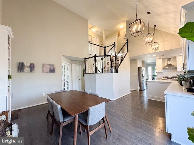 dining area featuring dark wood-style floors, baseboards, an inviting chandelier, and stairs