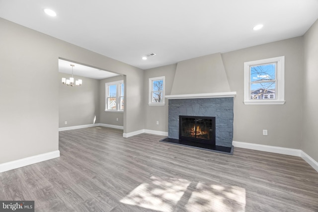 unfurnished living room featuring a stone fireplace, recessed lighting, wood finished floors, and baseboards