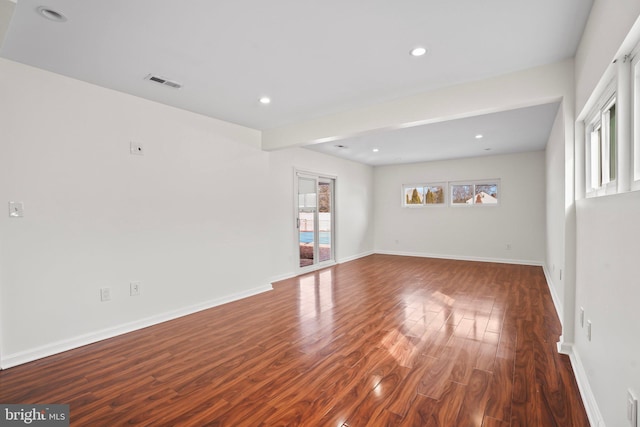 empty room featuring baseboards, visible vents, dark wood-type flooring, and recessed lighting