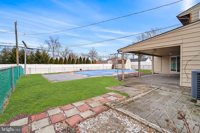 view of yard with an outbuilding, a fenced backyard, a storage shed, a fenced in pool, and a patio area