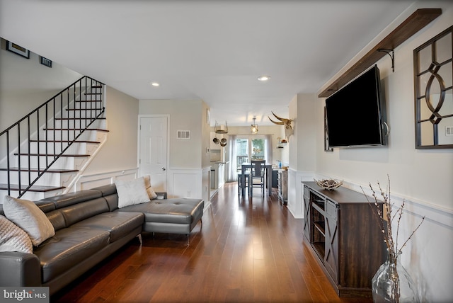 living area featuring visible vents, a wainscoted wall, wood finished floors, stairs, and a decorative wall