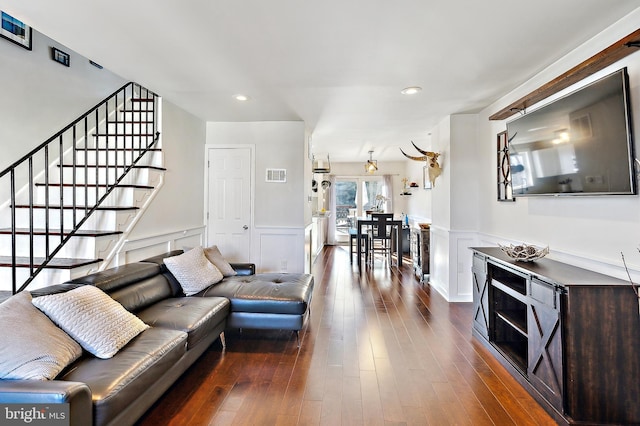 living area featuring stairs, dark wood-style flooring, wainscoting, and visible vents