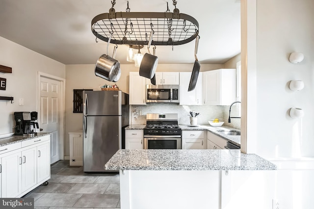 kitchen featuring backsplash, appliances with stainless steel finishes, white cabinets, a sink, and a peninsula