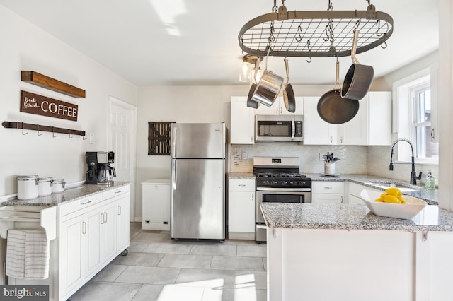 kitchen with stainless steel appliances, backsplash, a sink, and white cabinets