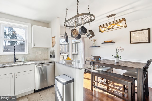 kitchen featuring a sink, light stone counters, decorative backsplash, and stainless steel dishwasher