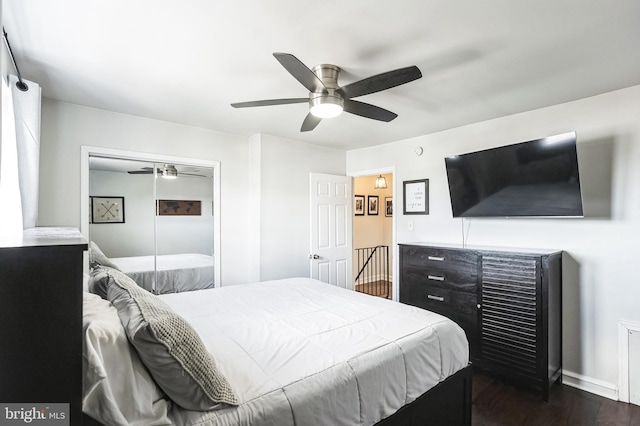 bedroom featuring dark wood-type flooring, a closet, baseboards, and a ceiling fan