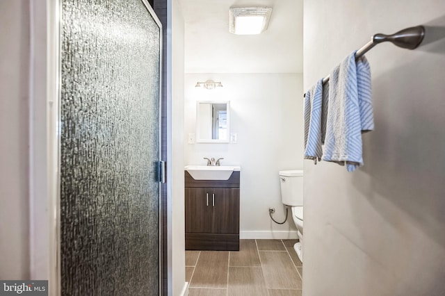 bathroom featuring baseboards, a shower stall, toilet, and vanity