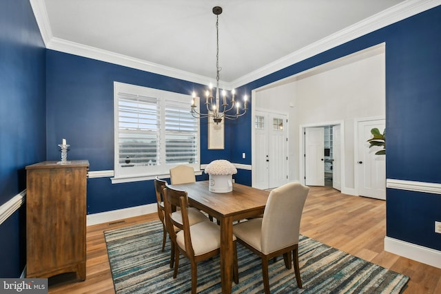 dining room with baseboards, ornamental molding, wood finished floors, and a notable chandelier