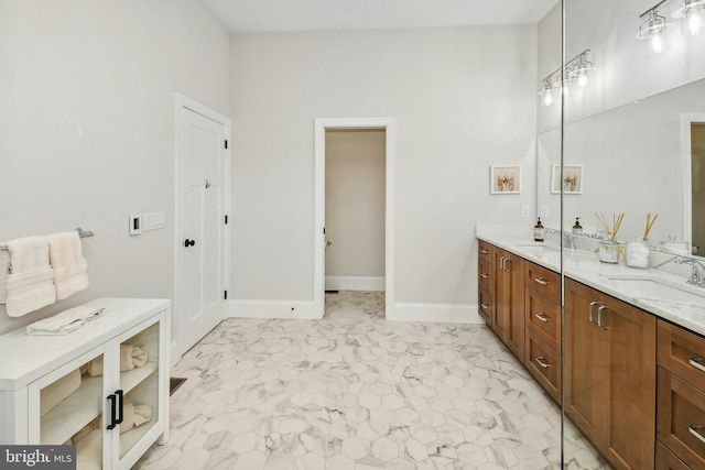 bathroom with double vanity, a sink, and baseboards