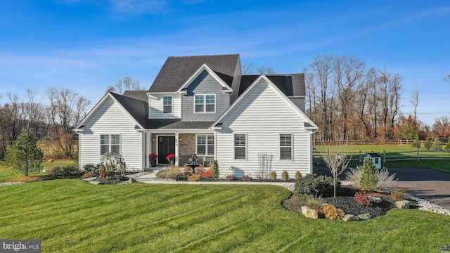 view of front of house featuring a front yard, stone siding, and driveway