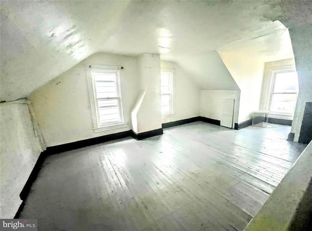 bonus room featuring light wood finished floors, baseboards, and vaulted ceiling