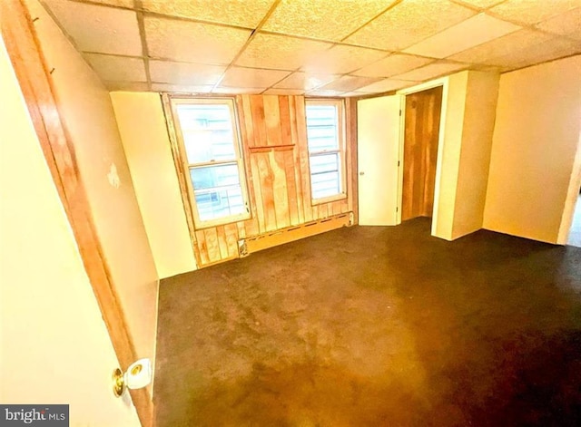 carpeted spare room with baseboard heating and a drop ceiling