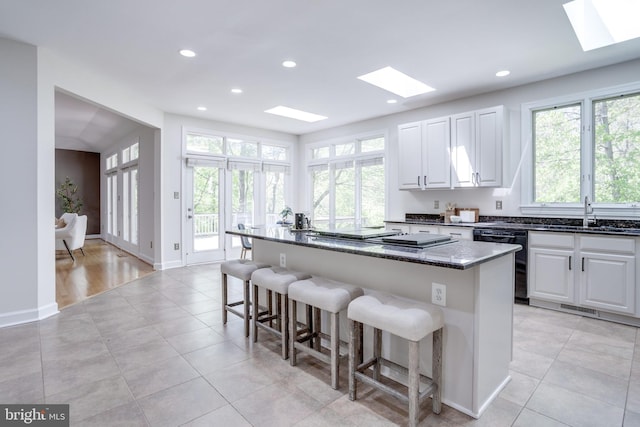 kitchen featuring a sink, a breakfast bar, dishwasher, and a skylight