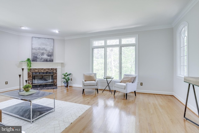 living area with baseboards, ornamental molding, wood finished floors, and a premium fireplace