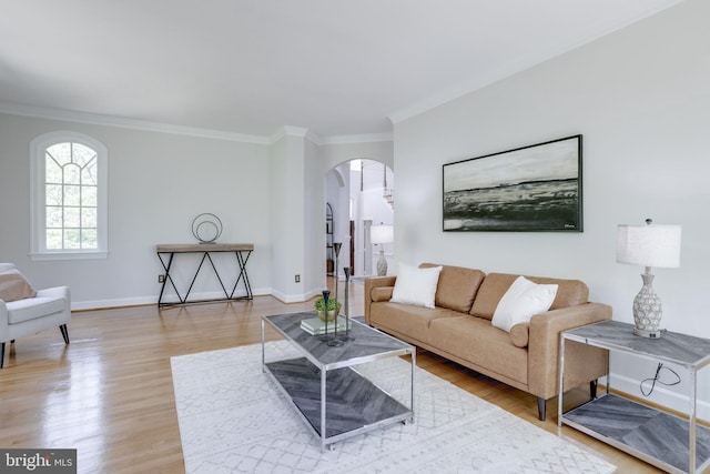 living room with arched walkways, baseboards, ornamental molding, and wood finished floors