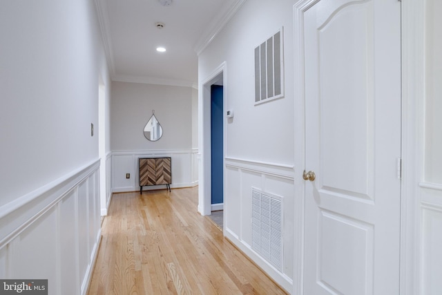 hallway featuring crown molding, visible vents, and a decorative wall