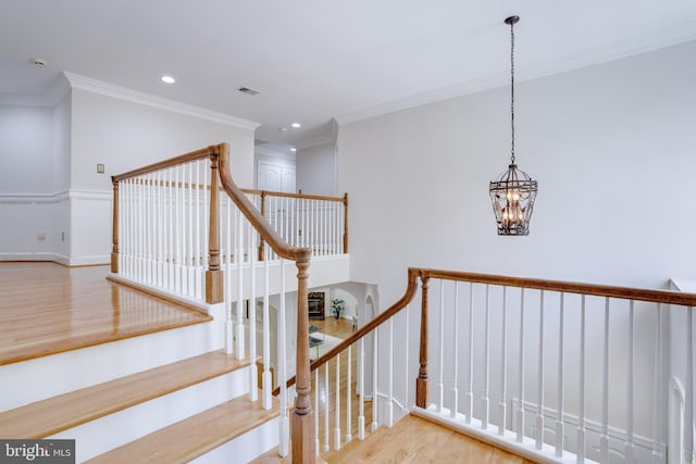 stairway featuring visible vents, wood finished floors, a chandelier, ornamental molding, and recessed lighting