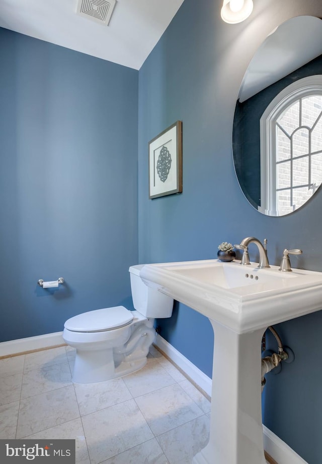 half bathroom with visible vents, baseboards, and toilet
