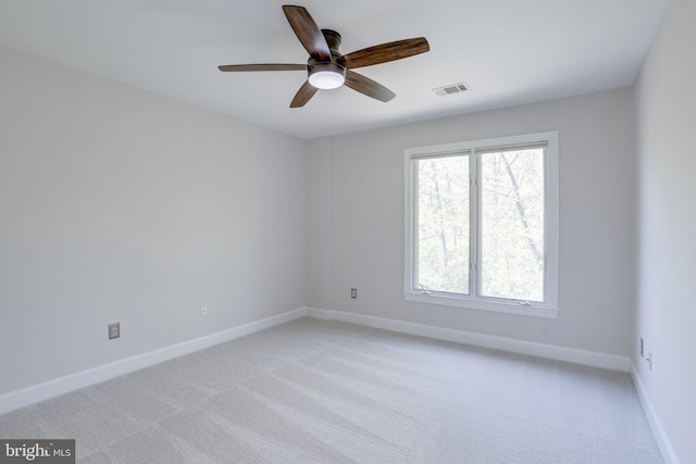 spare room with baseboards, light carpet, a ceiling fan, and visible vents