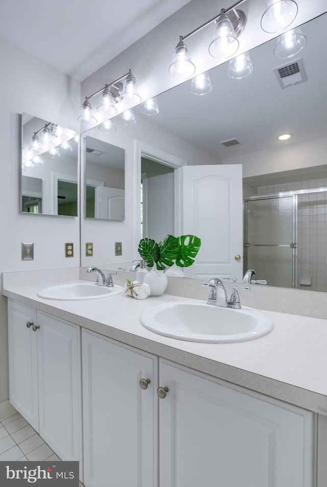 bathroom with a sink, a stall shower, double vanity, and visible vents