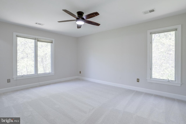 unfurnished room with baseboards, ceiling fan, light carpet, and visible vents