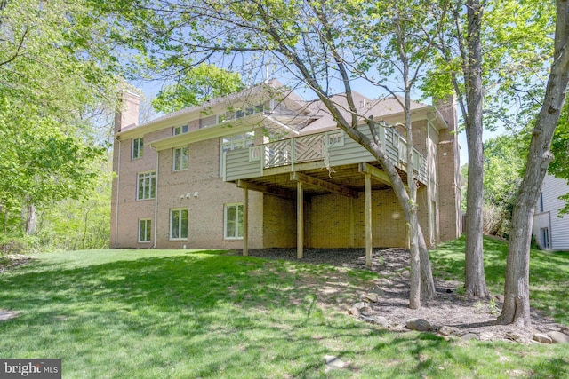 rear view of property with a lawn, brick siding, a chimney, and a deck