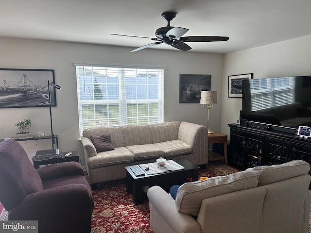 living area with dark colored carpet and ceiling fan