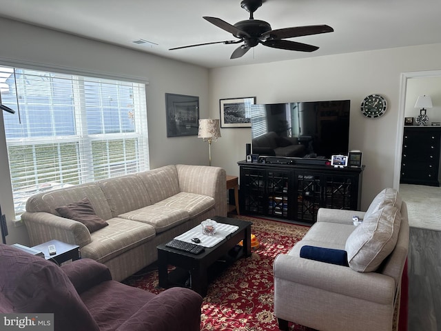 carpeted living area featuring visible vents and a ceiling fan