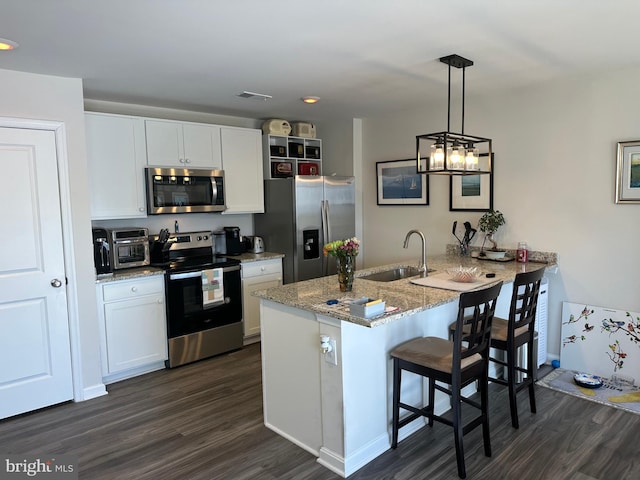 kitchen featuring pendant lighting, stainless steel appliances, white cabinetry, a sink, and a peninsula