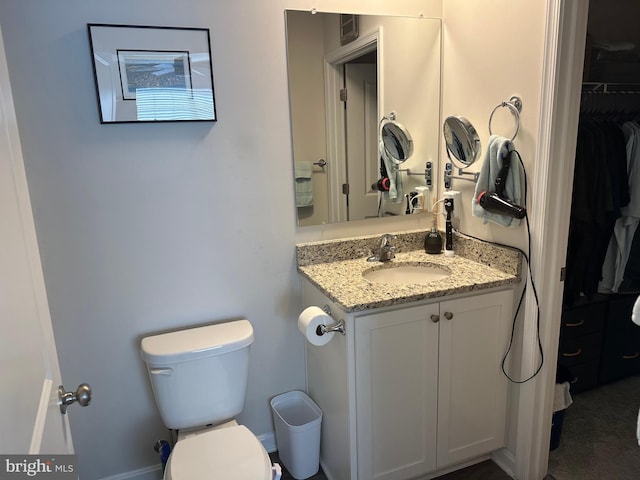 bathroom with toilet, visible vents, a walk in closet, and vanity