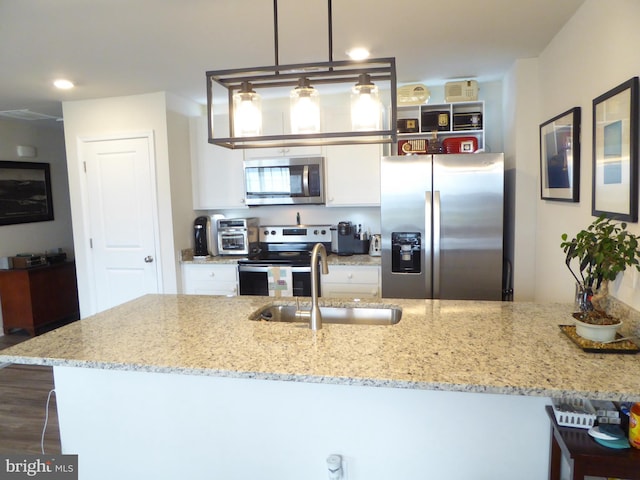 kitchen with light stone counters, hanging light fixtures, stainless steel appliances, white cabinetry, and a sink