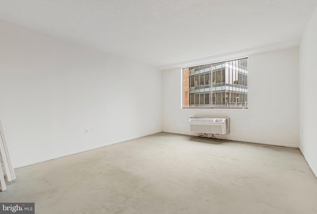 empty room featuring unfinished concrete flooring and an AC wall unit