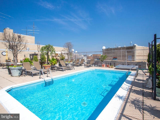 community pool with a patio area and fence